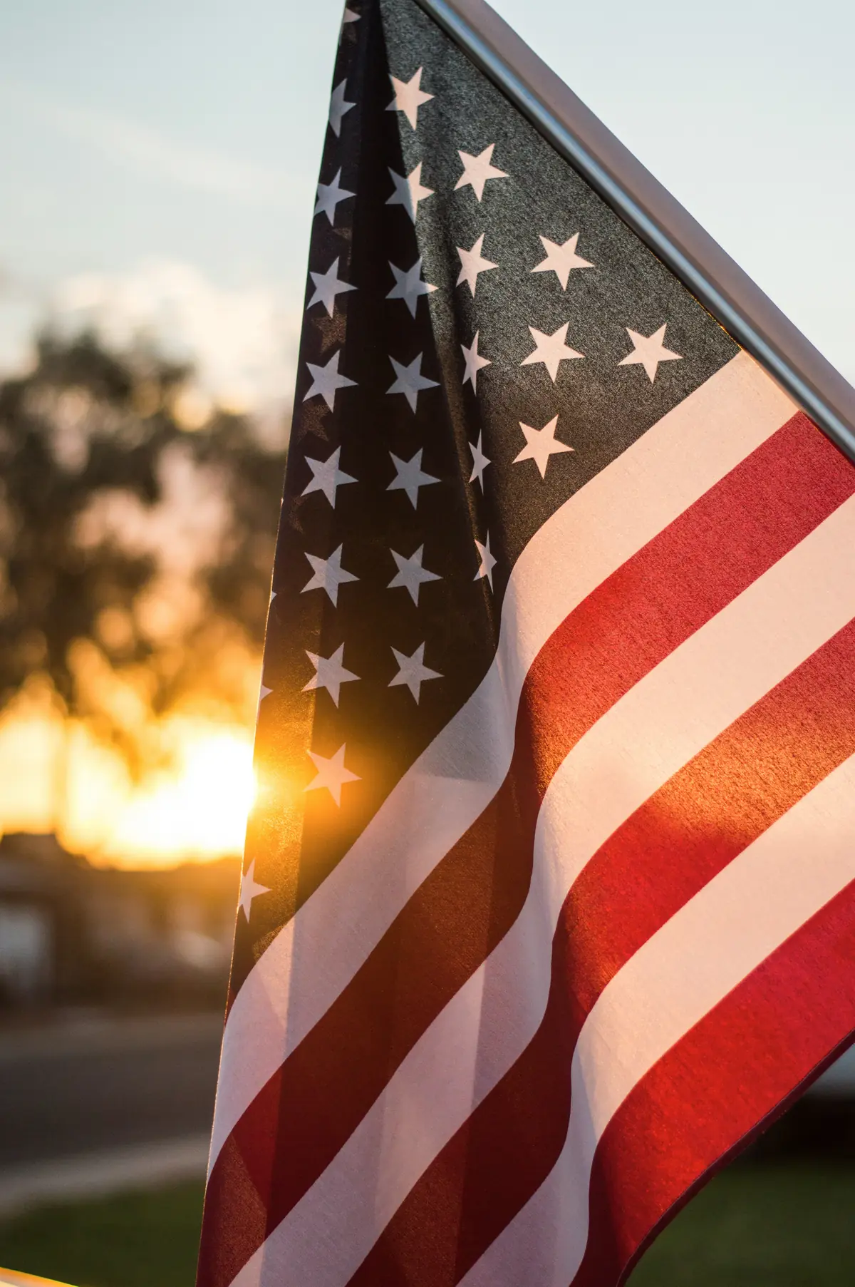 An American flag backlit by low golden sun
